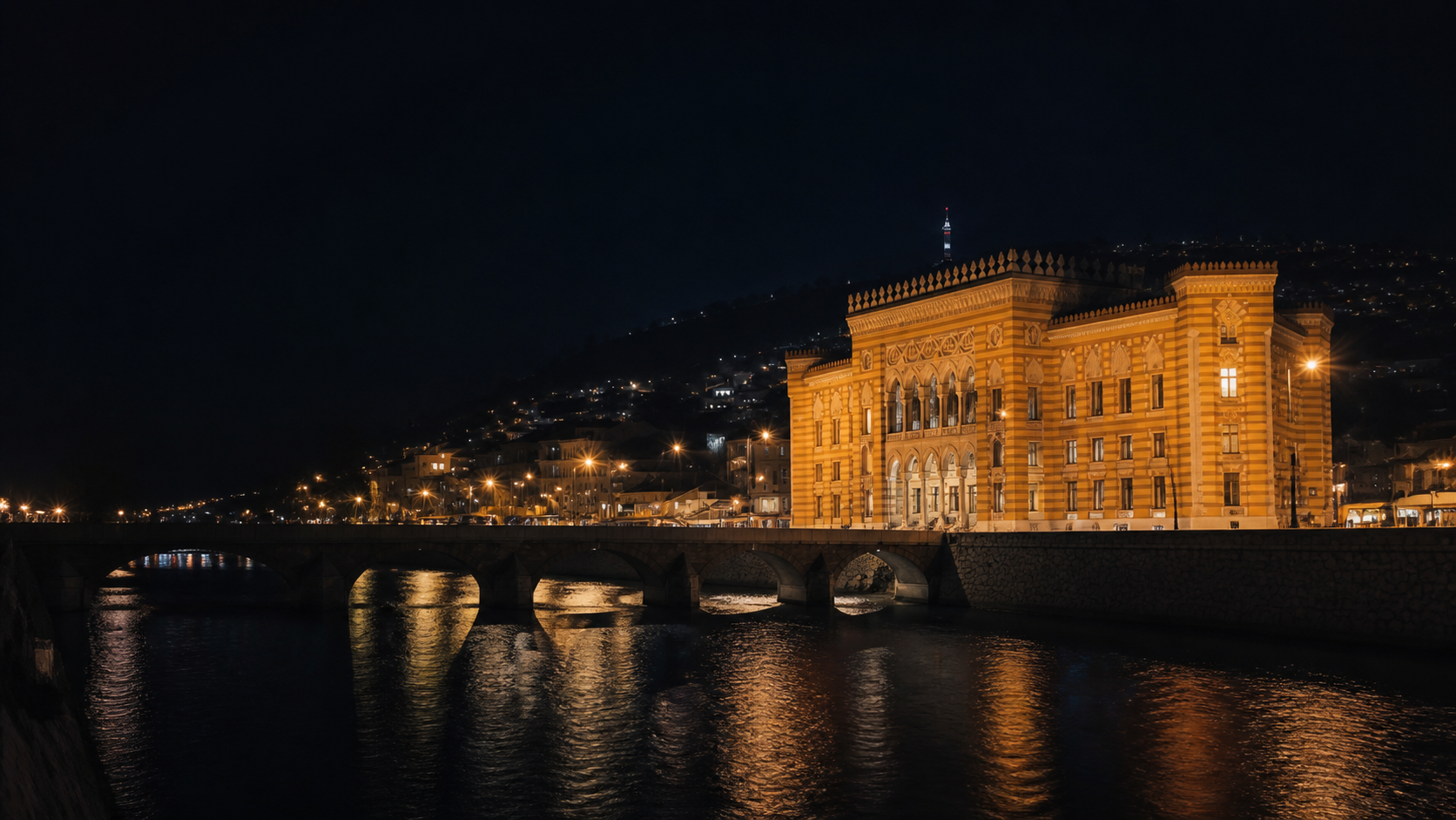 Sarajevo City Hall illuminated at night beside the Miljacka river